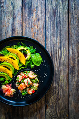Salmon ceviche with lemon, mango and avocado on wooden table
