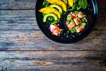 Salmon ceviche with lemon, mango and avocado on wooden table

