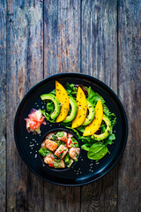 Salmon ceviche with lemon, mango and avocado on wooden table
