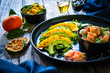 Salmon ceviche with lemon, mango and avocado on wooden table
