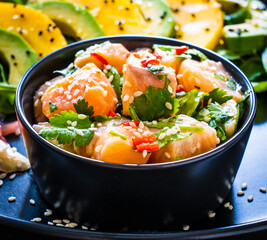 Salmon ceviche with lemon, mango and avocado on wooden table
