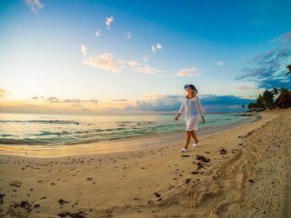 Woman walking on sunny, tropical beach at daybreak
