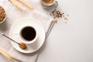 Barley coffee in white cup, beans and ears of barley on white background. Warming caffeine free beverage alternative coffee. View from above. Copy space.