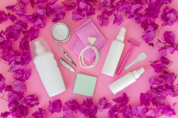 Women's personal care products on a pink background. Sanitary pads, razor, cream, spray, tweezers.