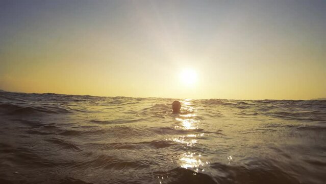 Drowning man looking for help from lifeguard on beach at sunset, slow motion