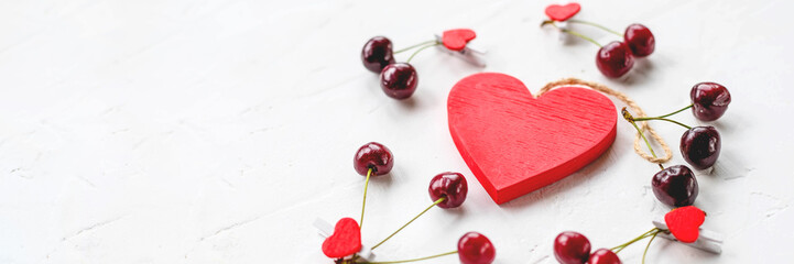 Fototapeta na wymiar fresh seasonal red cherry berry fruit with healthy vitamins on white background and red heart as love symbol of valentines day, holiday.Love is cure. Valentine's Day inspiration.