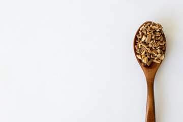 Burdock Root Herb Herbal Medicine. Dried Finely Chopped Root in a Wooden Spoon on a White Background with Copy Space.