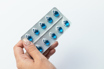 Hand holding a pack of blue pills, headache pills, pain relief