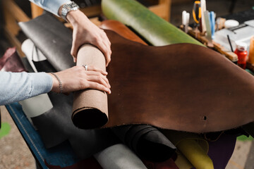 Obraz premium Leather craftsman is touching roll of genuine leather in the workshop. Rolls of genuine leather of different colors in leather products workshop.