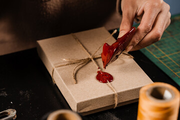 Process of sealing waxing on gift packaging in workshop. Craftsman is burning sealing wax and...