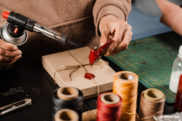 Process of sealing waxing on gift packaging in workshop. Craftsman is burning sealing wax and...
