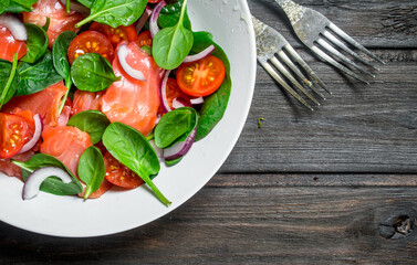 Fish salad. Salad with slices of salmon, tomatoes and spinach with lime juice.