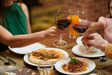 Family toasting with glasses of wine and juice over restaurant table