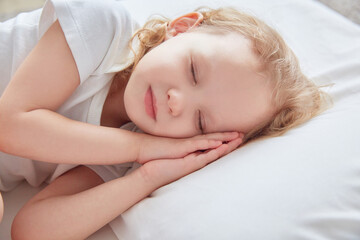 Fototapeta na wymiar Little girl sleeps on a white pillow.