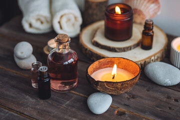 Fototapeta na wymiar Concept of natural essential organic oils, Bali spa, beauty treatment, relax time. Atmosphere of relaxation, pleasure. Candles, towels, dark wooden background. Alternative oriental medicine