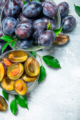 Pieces and whole fresh plums in glass bowls.