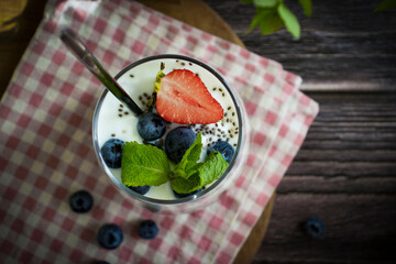 Yogurt, chia seeds, blueberries, strawberries, raspberries, mint, kiwi on a dark background