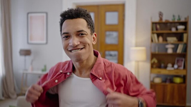 Carefree charismatic African American guy admires his appearance, looks at camera like in a mirror