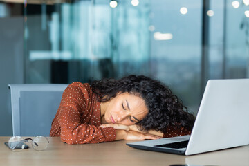 Beautiful tired hispanic woman sleeping on desk, close-up business woman with closed eyes napping...
