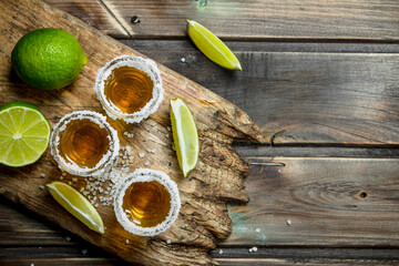 Tequila in a shot glass of salt on the cutting Board. - 561368888