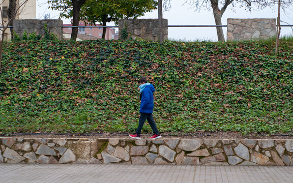 Ni&ntilde;o caminando sobre un bordillo en un parque en una tarde de invierno.