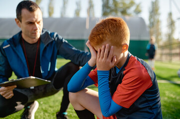 Coach comforting crying little soccer player after missed goal