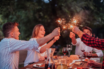 Group of happy friends celebrating holiday vacation using sprinklers and drinking red wine while...