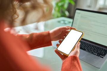 Over shoulder view of woman holding mobile phone with white blank mock up cellular screen apps...