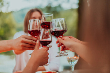 Group of happy friends toasting red wine glass while having picnic french dinner party outdoor...