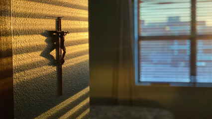 Cross on the wall with sun shining in with shadow