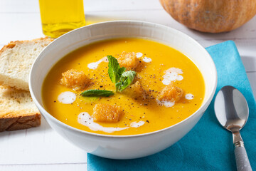 Close-up of pumpkin and carrot cream decorated with croutons and sour cream.