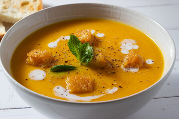 Close-up of pumpkin and carrot cream decorated with croutons and sour cream.