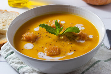 Close-up of pumpkin cream soup decorated with croutons and sour cream.
