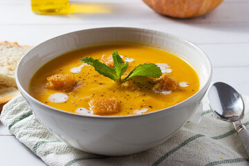 Close-up of pumpkin cream soup decorated with croutons and sour cream.