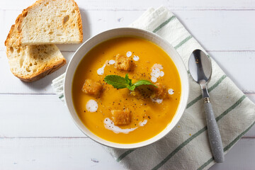 Cream of pumpkin and carrot soup on a rustic wooden background. Top view. Copy space.