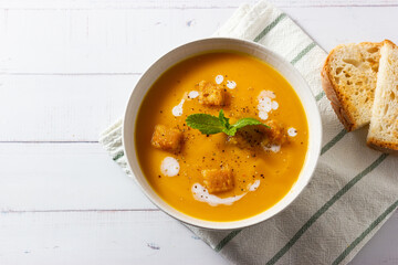 Cream of pumpkin and carrot soup on a rustic wooden background. Top view. Copy space.