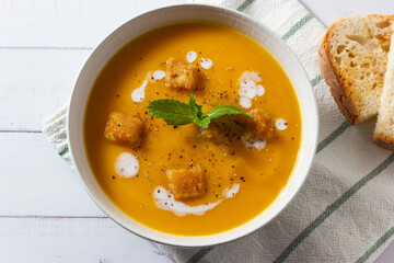 Cream of pumpkin and carrot soup on a rustic wooden background. Top view. Copy space.