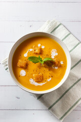 Cream of pumpkin and carrot soup on a rustic wooden background. Top view. Copy space.