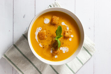 Cream of pumpkin and carrot soup on a rustic wooden background. Top view. Copy space.