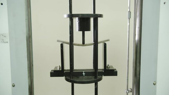 Sheet of hollow polycarbonate breaks under pressure of testing press. Laboratory investigates stability and flexibility of plastic building materials