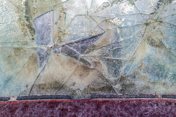 The cracked rear window of a rusty antique car