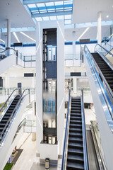 Fototapeta premium Escalator and elevator with hydraulic system in atrium with skylights