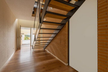 Interior stairwell of a single-family house with several floors built with metal and glass railings and wooden steps and chestnut hardwood floors