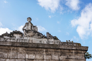 Naklejka premium Stone arch at the entrance to a small palace with a female sculpture on top