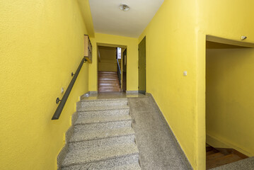 Gray granite stairs of a house with an unusable ramp due to its steepness and yellow walls