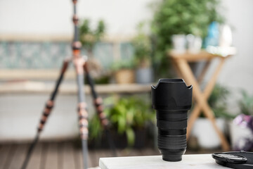 A 24-70 focal length black lens on a white table with an extended tripod in the background
