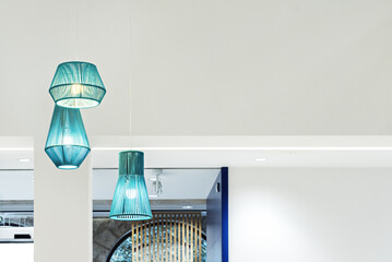 Decorative indoor lamps made of blue rope hanging in a spacious room with plain white painted walls...