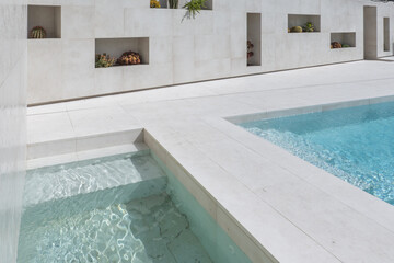 Pools of a single-family house with marble floors and niches in the wall full of cacti and...
