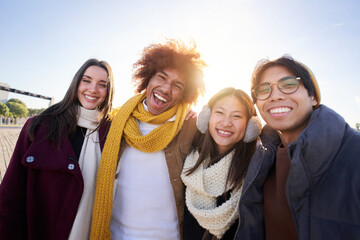 Portrait of Mixed race group of happy colleagues looking at camera and having fun in winter clothes. Young smiling people laughing together enjoy the community. Cheerful face of young students
