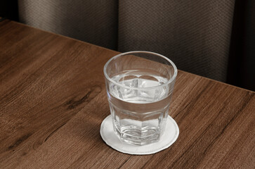 A glass of water on a wooden table. Clean clear water for drinking.
